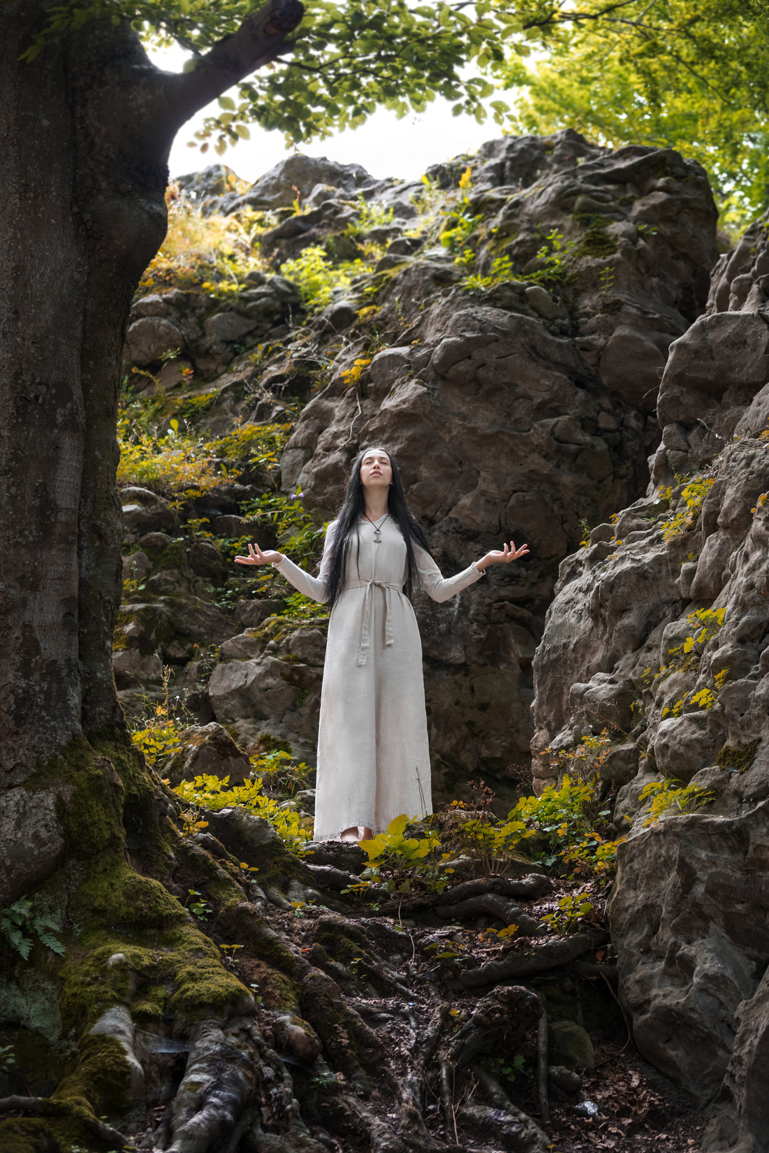 A Woman in Long Dress Meditating Near Big Rocks